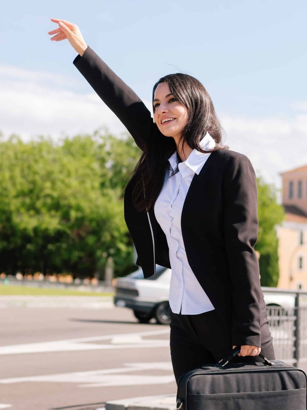 Vertical photo of a beautiful adult businesswoman calling a taxi on the city streets.
